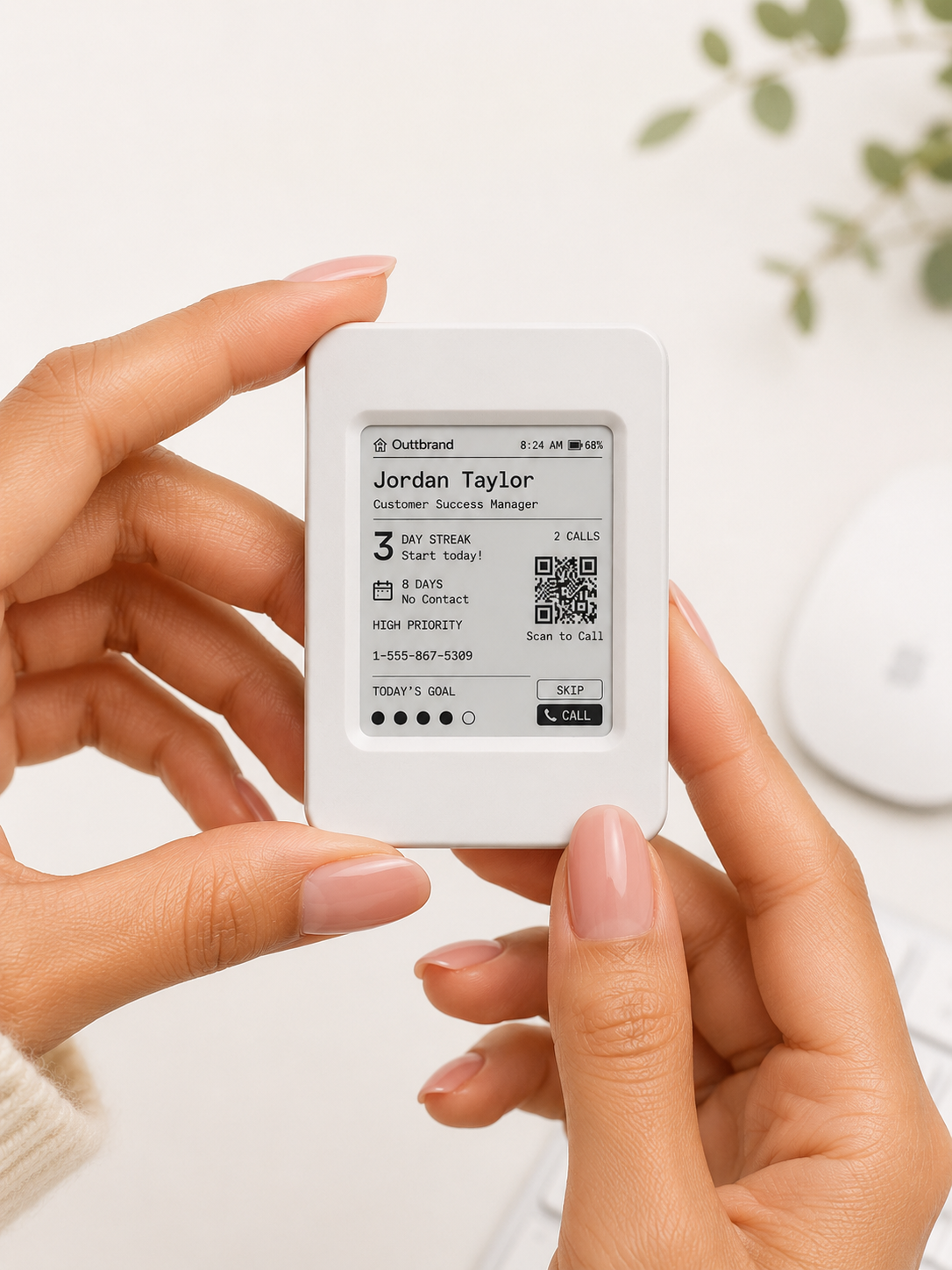 Hands holding the small Momentum e-paper device, showing the next contact to call