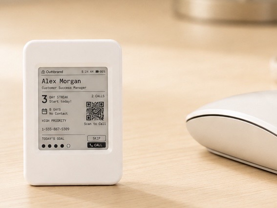 The small Momentum e-paper device sitting on a desk beside a mouse, showing the next contact, Alex Morgan, to call