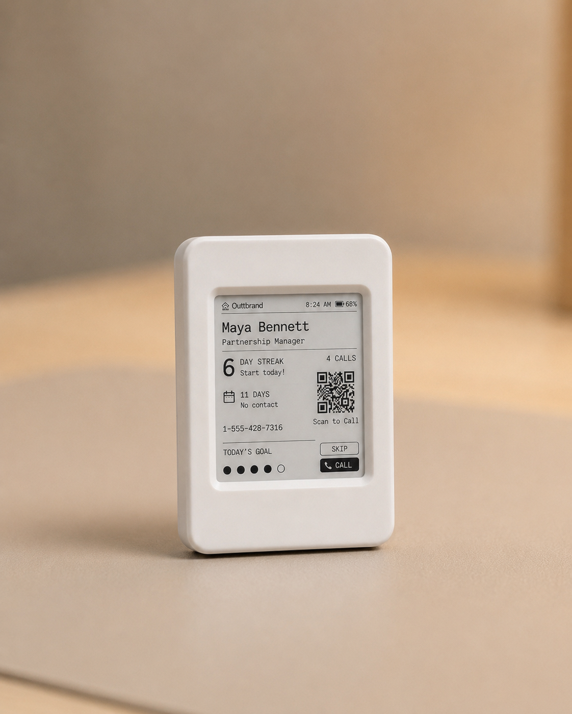 The Momentum e-paper device displaying a contact card with day streak, QR code, and call or skip actions